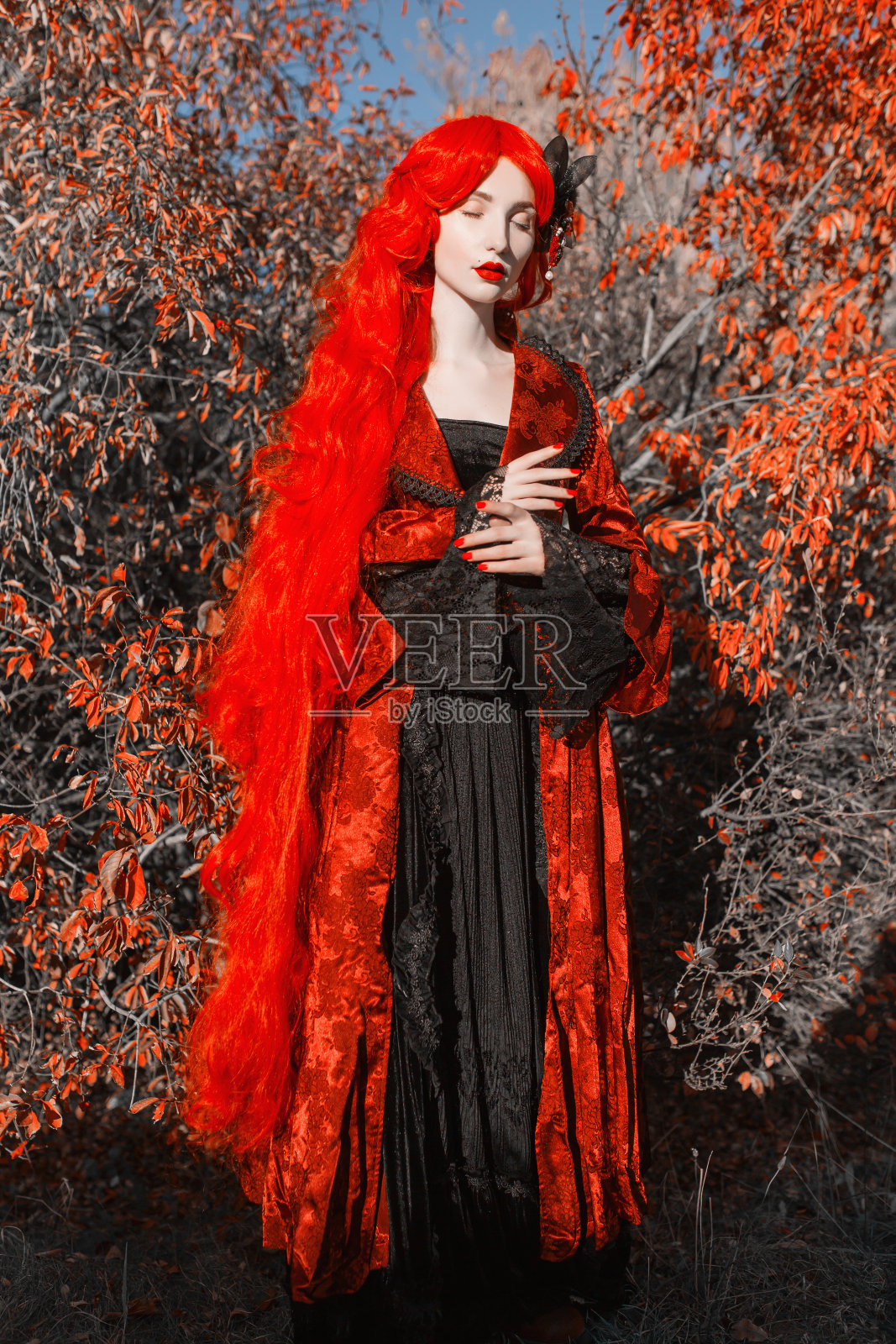 哥特式万圣节的外套。年轻的中世纪女王在秋天的背景。红头发的女士。苍白皮肤的吸血鬼。万圣节的中世纪服装。穿着哥特式服装的吸血鬼女王。童话动漫真人秀照片摄影图片