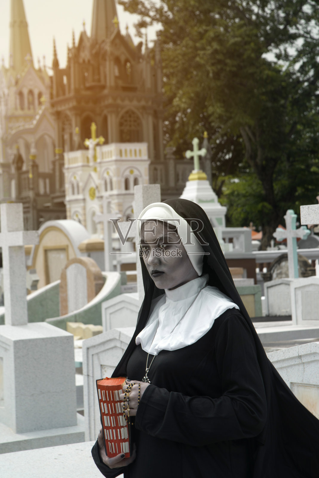 在黑暗神秘的教堂墓地中描绘一个幽灵、修女或魔鬼。照片摄影图片