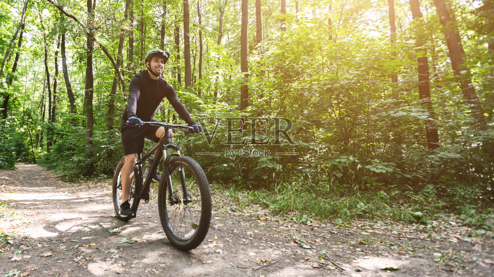 骑自行车的人骑在森林公路在太阳耀斑照片摄影图片