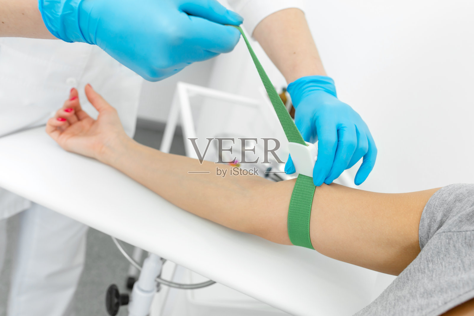 诊所里的护士拉紧一个年轻女孩手上的挽具，从静脉中抽取血液进行分析照片摄影图片