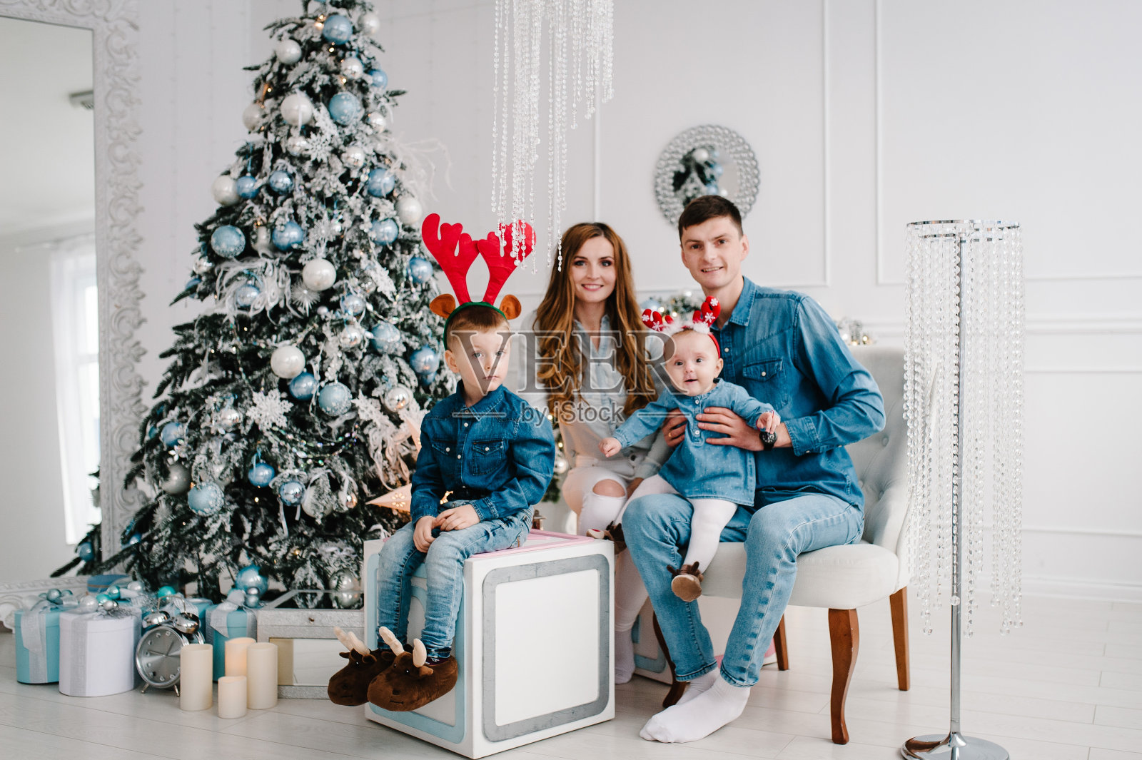 爸爸、妈妈抱着儿子和女儿靠近圣诞树。新年快乐，圣诞快乐。圣诞装饰室内。家庭度假的概念。关闭了。照片摄影图片