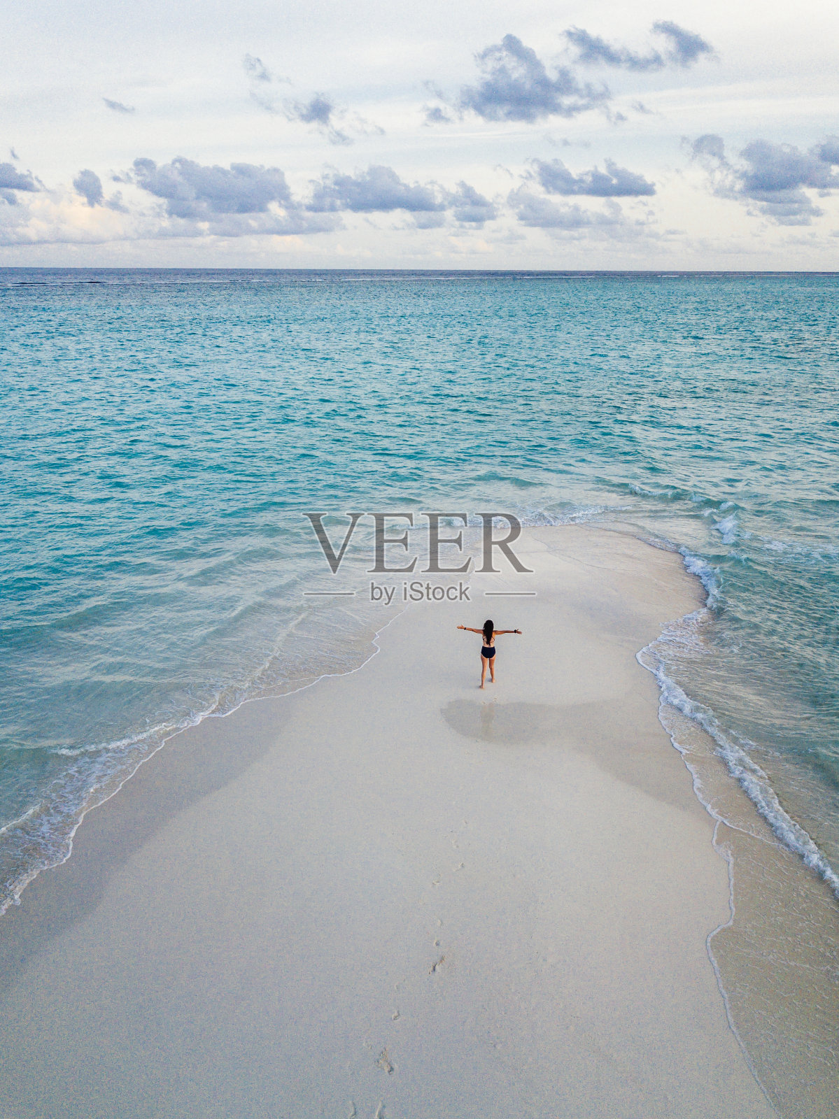 日落时分，年轻的成年女子站在马尔代夫碧绿的沙滩上照片摄影图片