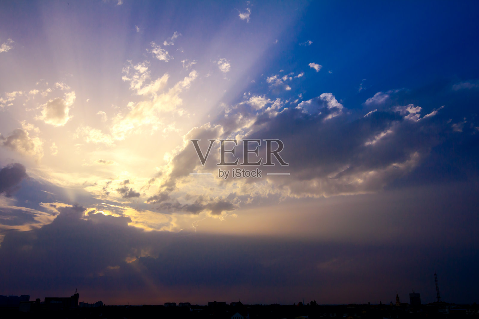 日落时，在绚丽的天空和积云下的城市剪影照片摄影图片