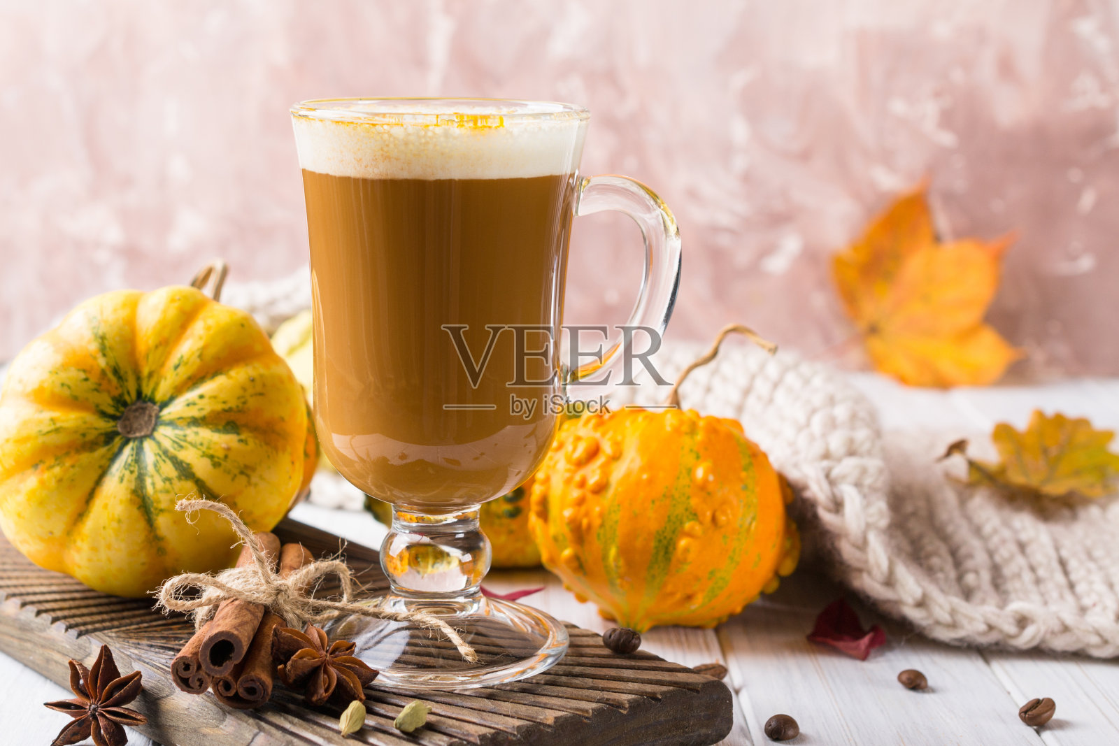 一杯南瓜香料拿铁，上面有生奶油和秋季香料，还有秋季装饰。传统咖啡饮品为秋冬假期，拷贝空间。照片摄影图片