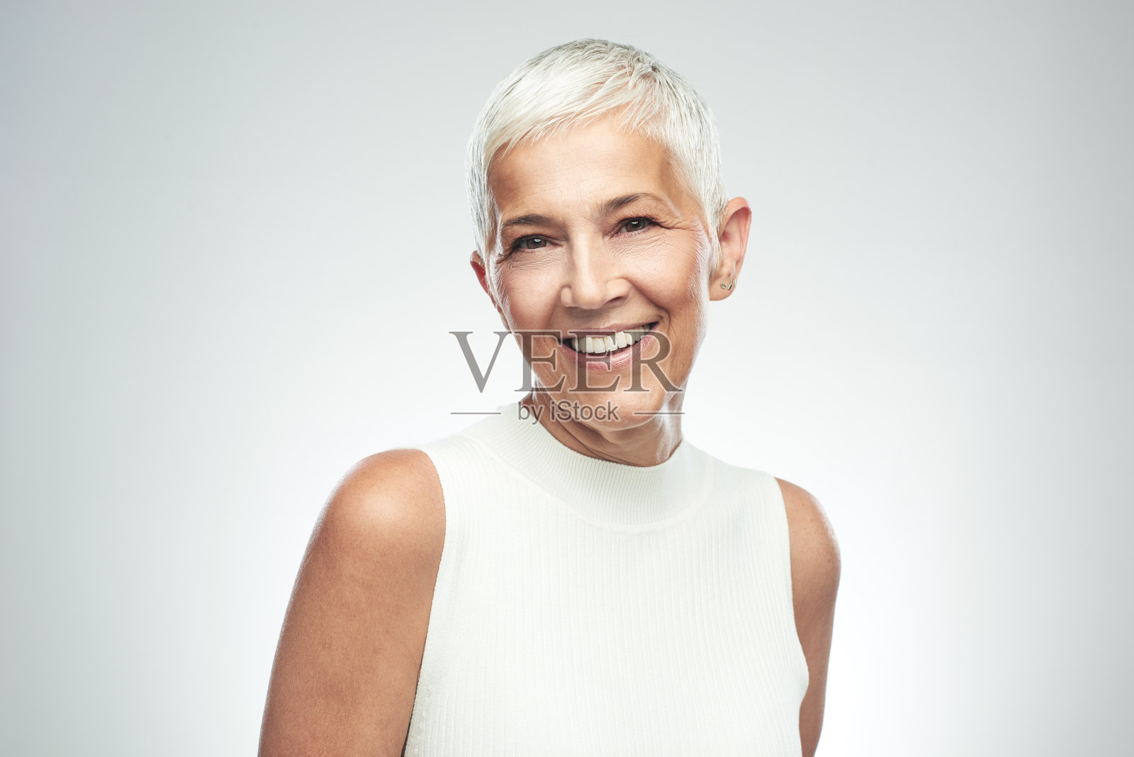 老妇人在灰色背景前摆姿势。照片摄影图片