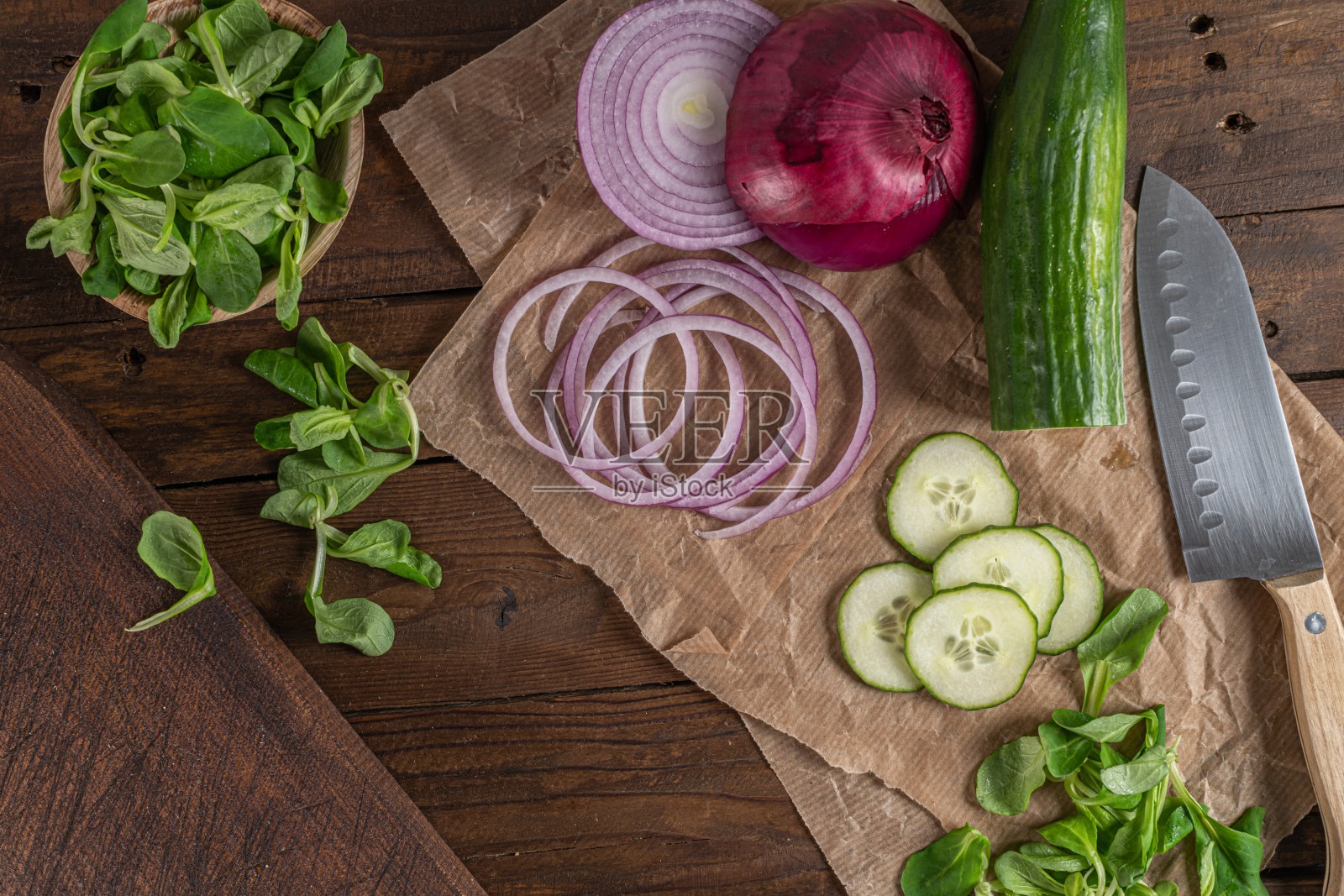 木制砧板的顶视图在旧的木质桌面与桌布，切片红洋葱，黄瓜和玉米沙拉照片摄影图片