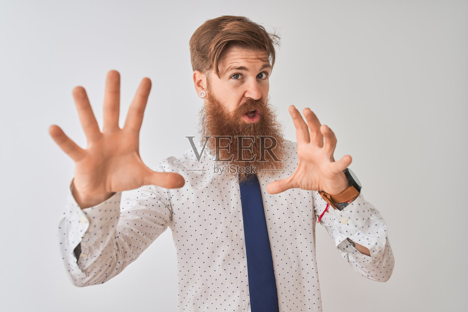 年轻的红头发爱尔兰商人站在孤立的白色背景害怕和恐惧的表情停止手势与手，在震惊大叫。恐慌的概念。照片摄影图片