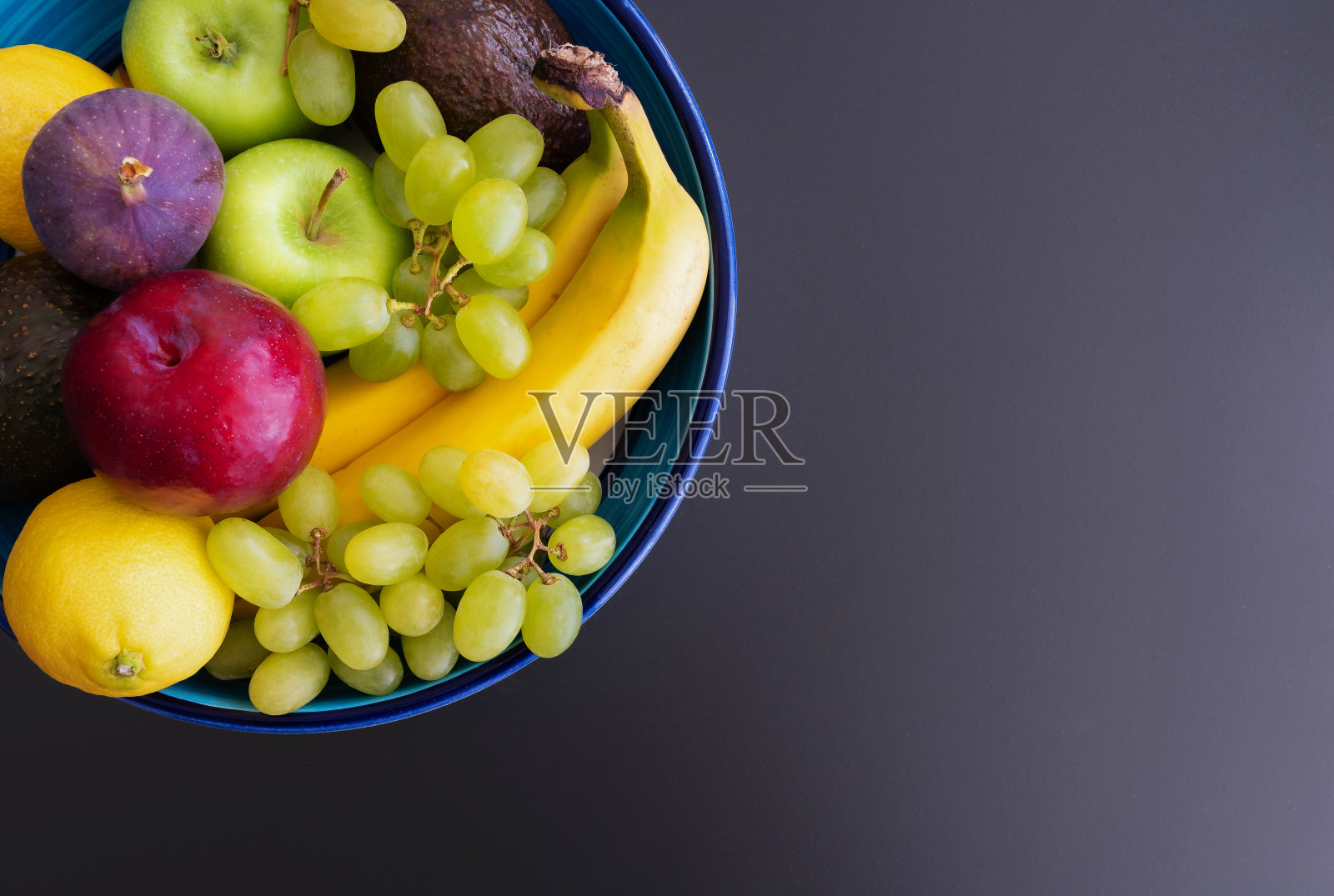 黑色背景上，盛满新鲜有机水果的陶碗照片摄影图片