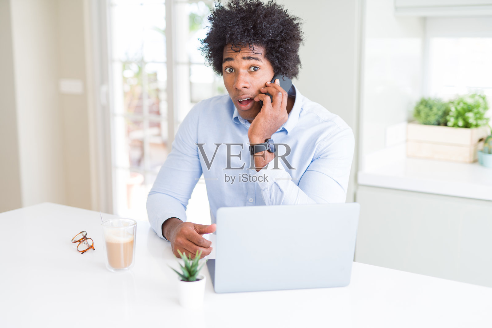 一位非洲裔美国商人在打电话时吓得脸上带着惊讶、害怕和兴奋的恐惧表情照片摄影图片