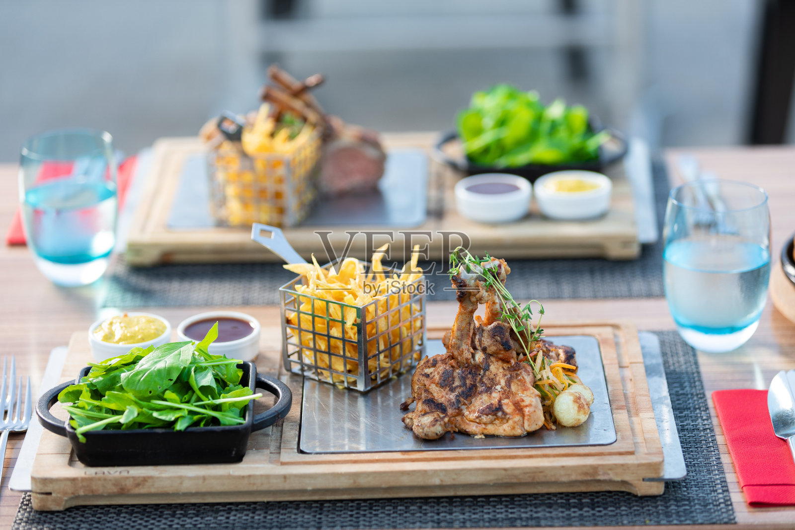 户外餐桌上的烤鸡臀和土豆片配蔬菜和绿色蔬菜。照片摄影图片