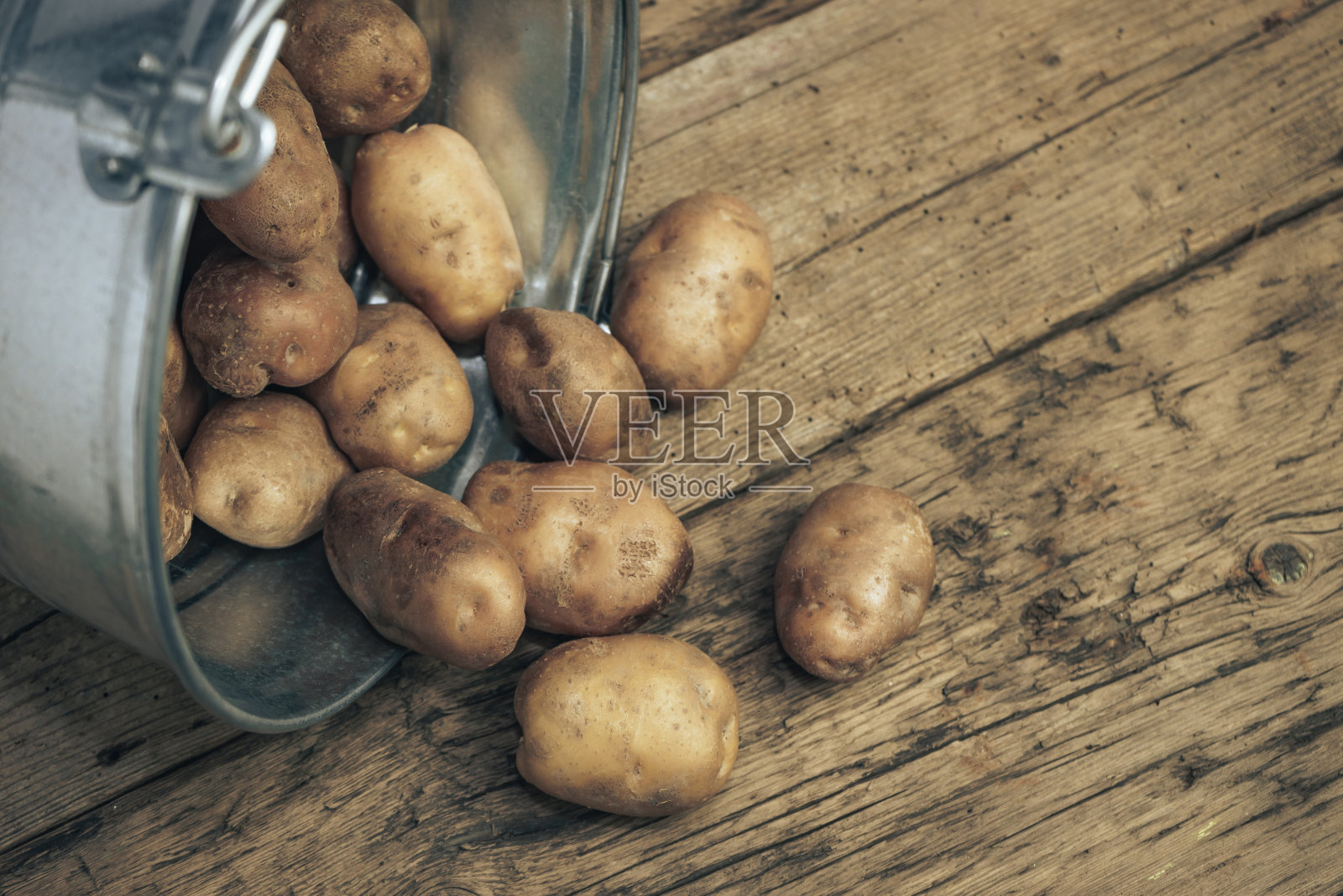 银篮子里的新鲜土豆放在旧橡木木桌上，背景很漂亮。前视图。照片摄影图片