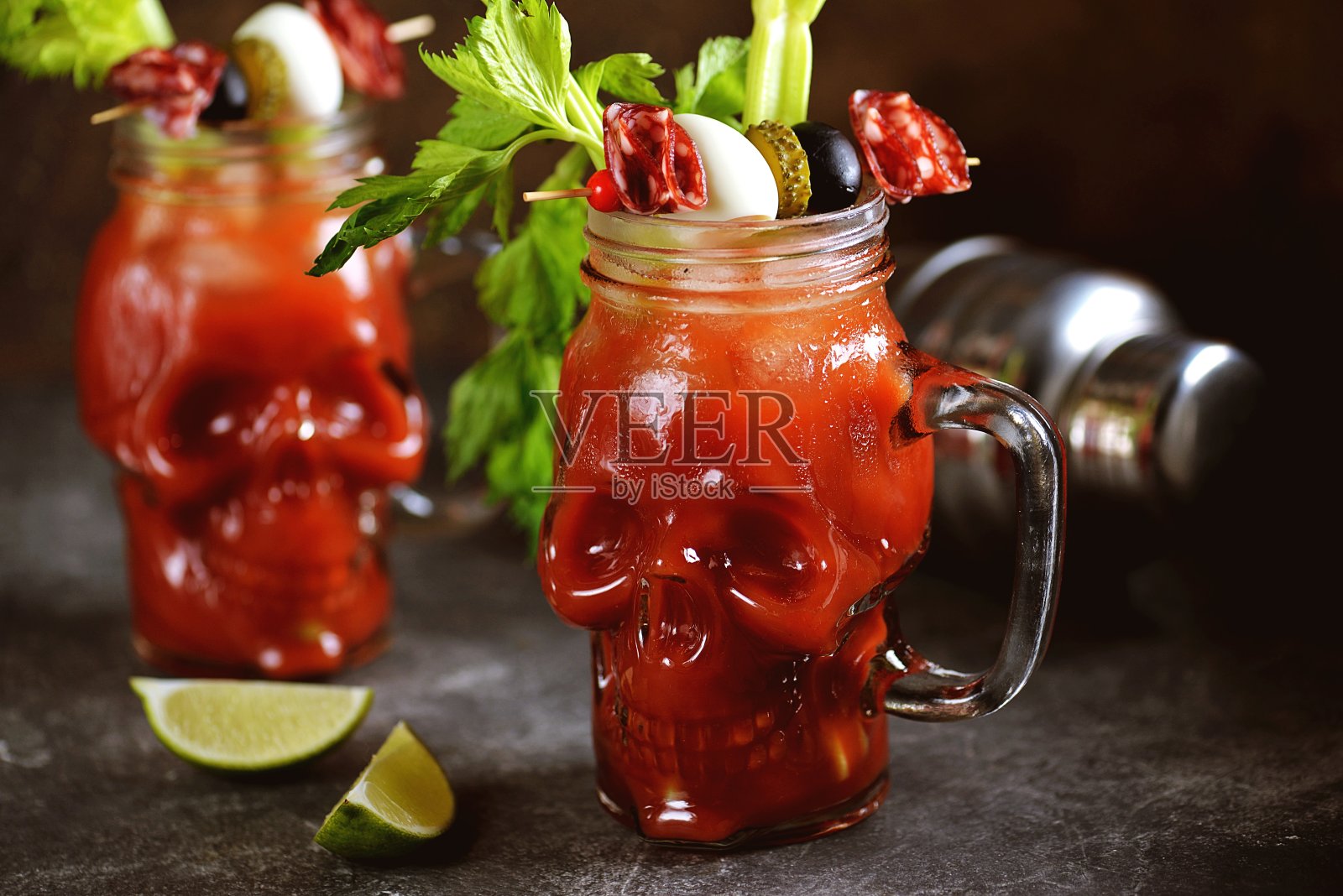 血腥玛丽玻璃头盖骨鸡尾酒，芹菜杆，粉盐，酸橙和罐头蔬菜点心。万圣节的饮料。照片摄影图片