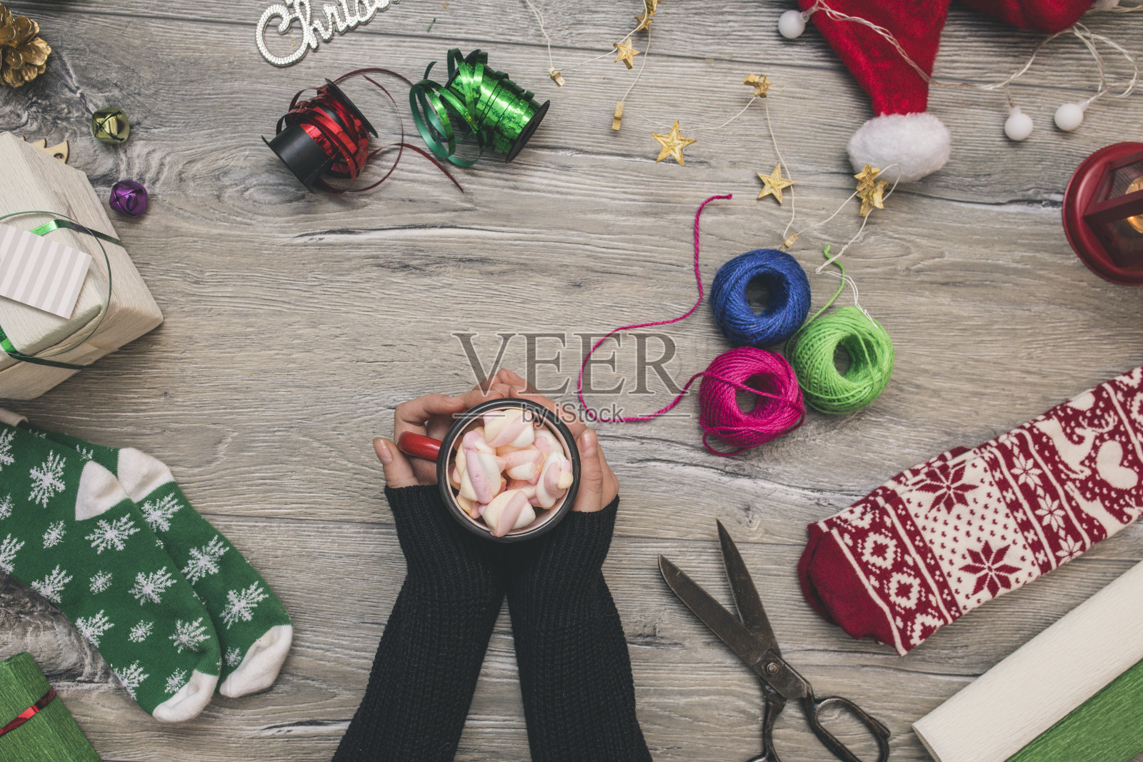 女人手里拿着咖啡杯，用牛皮纸包着圣诞礼物或礼物盒，用圣诞树树枝装饰顶视图照片摄影图片