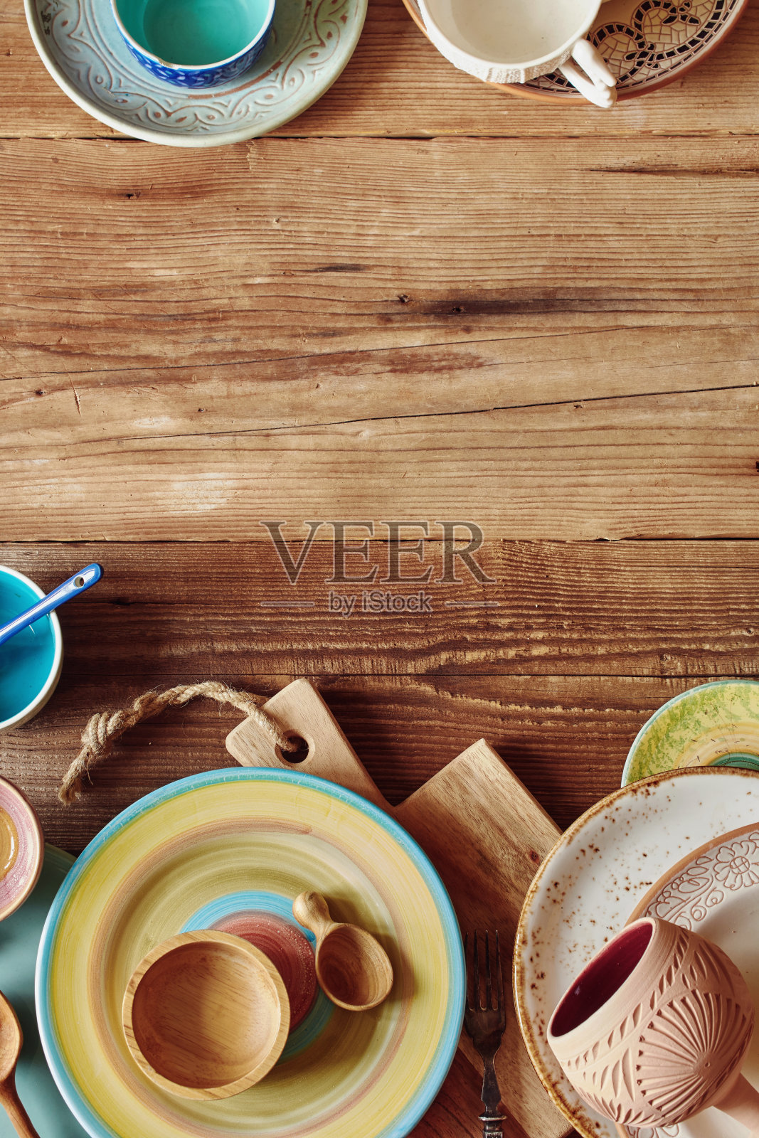 各种彩色陶瓷厨房盘子，碗和杯子与copyspace木桌。平的。照片摄影图片