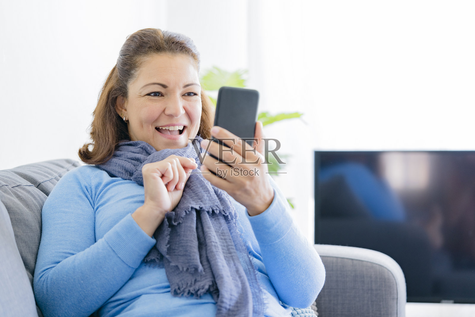 中年妇女在家里用智能手机看短信照片摄影图片