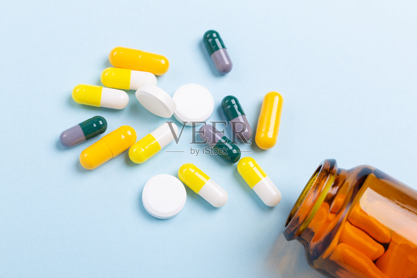 多色药片和药丸胶囊从玻璃瓶在蓝色的背景特写照片摄影图片