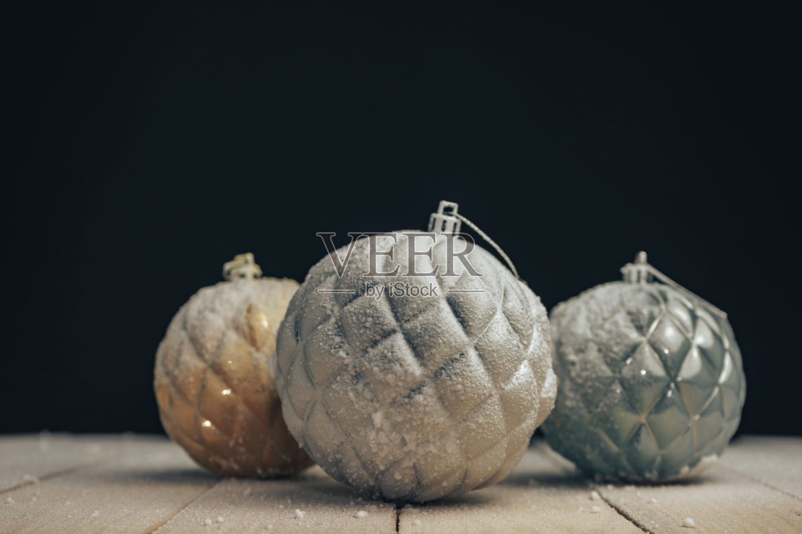 漂亮的圣诞小玩意放在一张新木桌上，后面是雪和黑色的背景。照片摄影图片