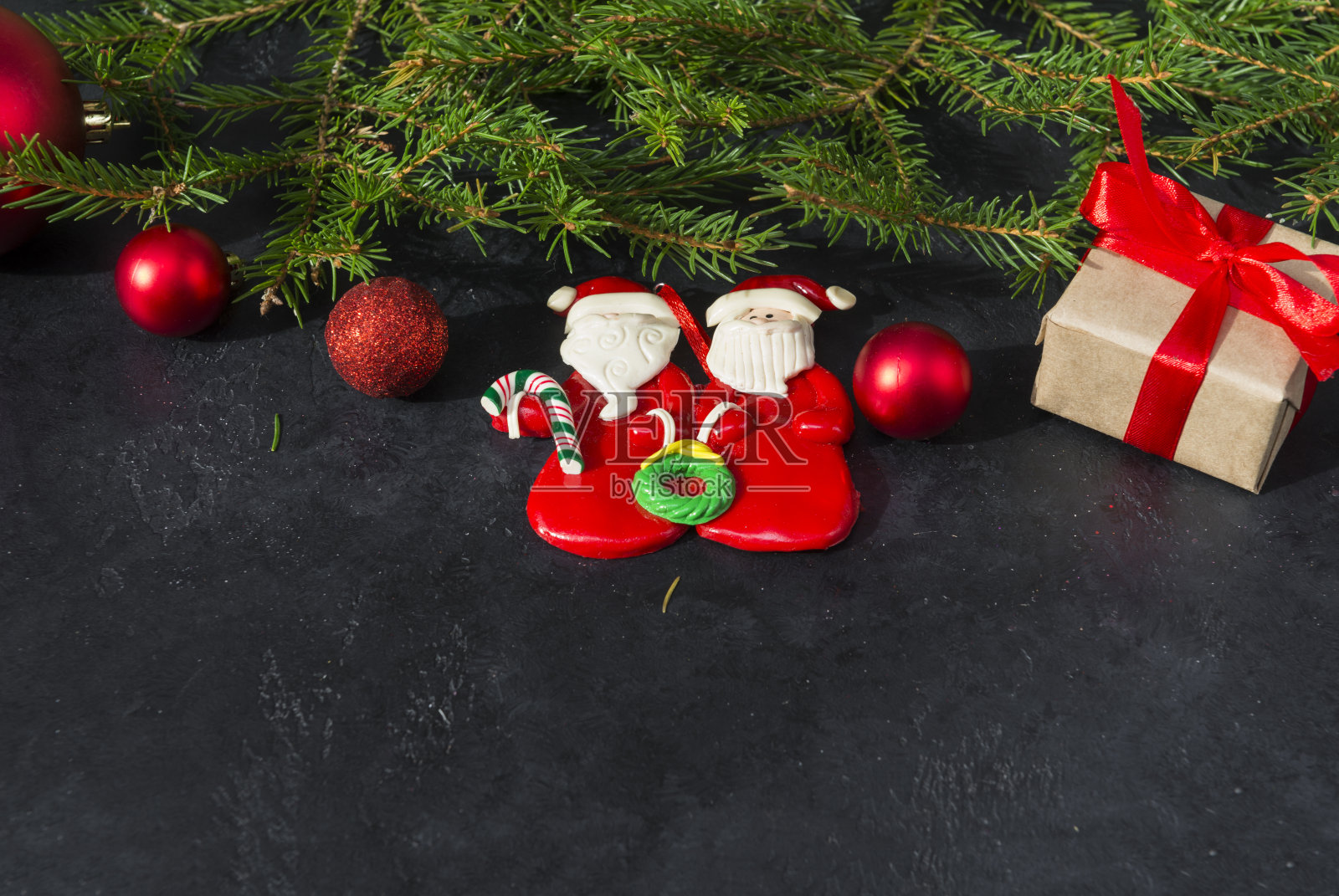 冷杉枝，用红丝带绑的礼盒，2个圣诞老人玩具，黑色背景上的红球，圣诞节照片摄影图片