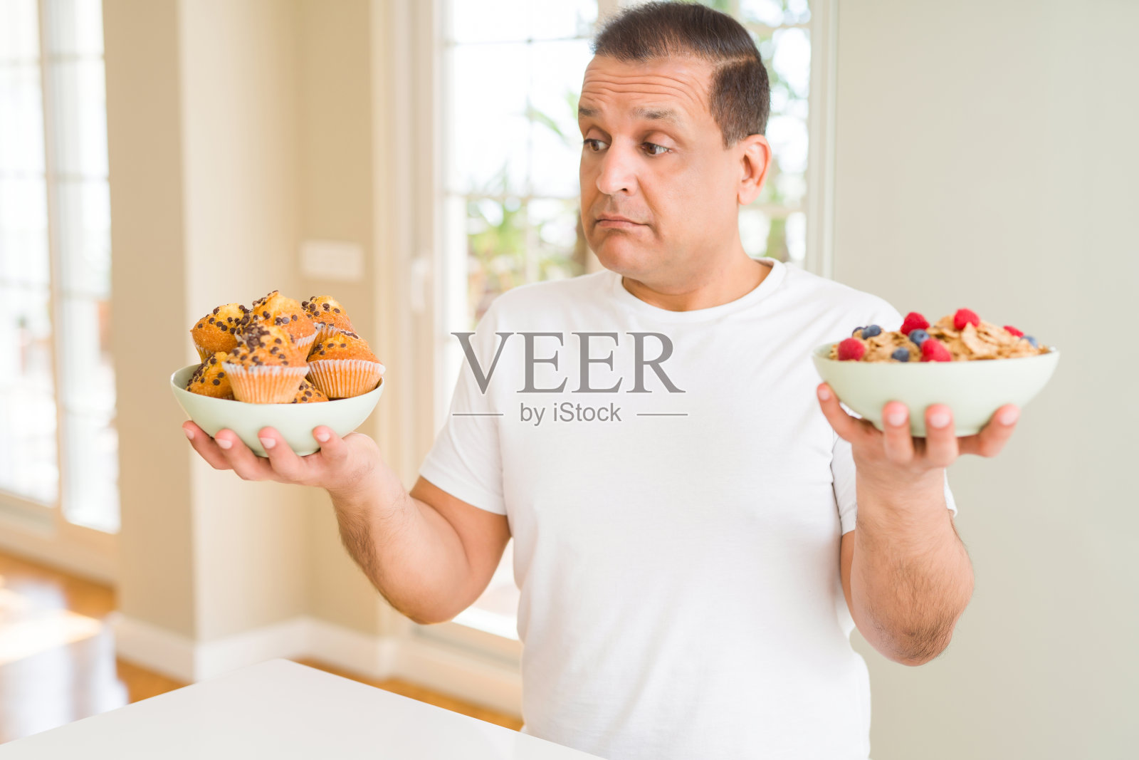 中年阿拉伯男子选择健康早餐或垃圾食品照片摄影图片