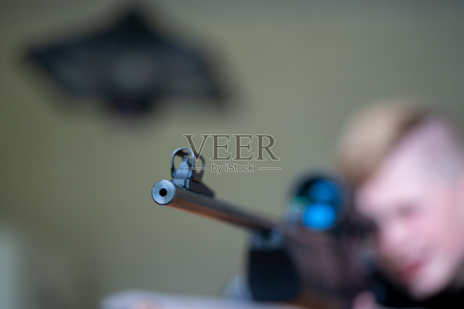 一个年轻人透过一支黑色步枪的瞄准镜瞄准照片摄影图片