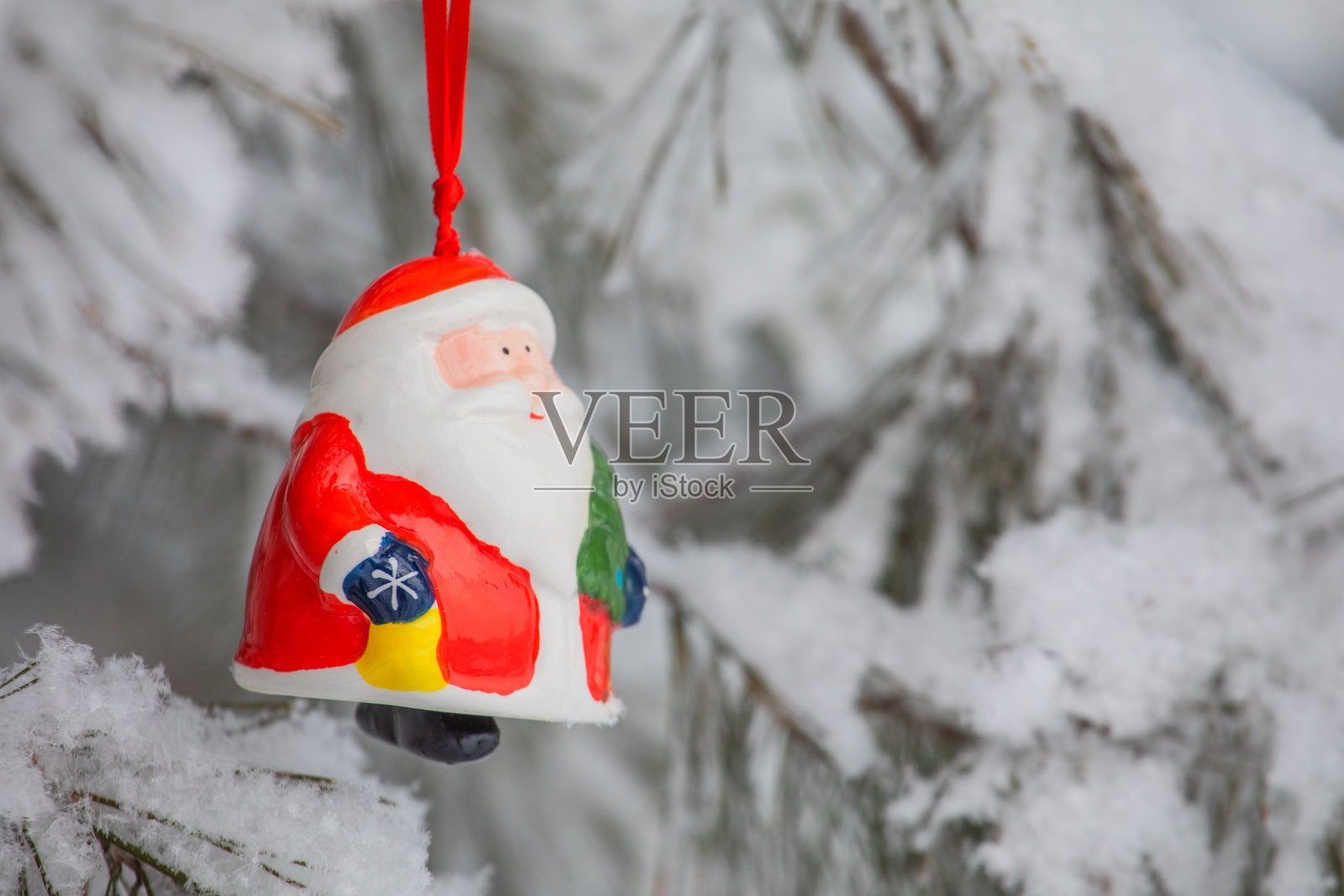 新年。圣诞节和装饰。玩具圣诞老人在森林的树枝上荡秋千。下雪照片摄影图片