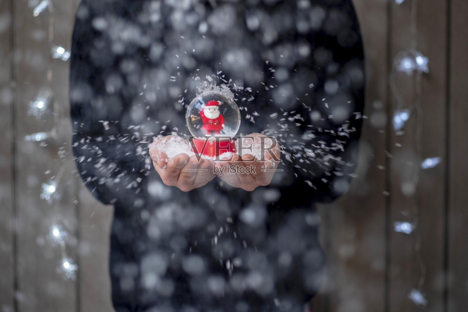 男人手里拿着一个小雪球，雪球里面有一个小圣诞老人带着雪照片摄影图片