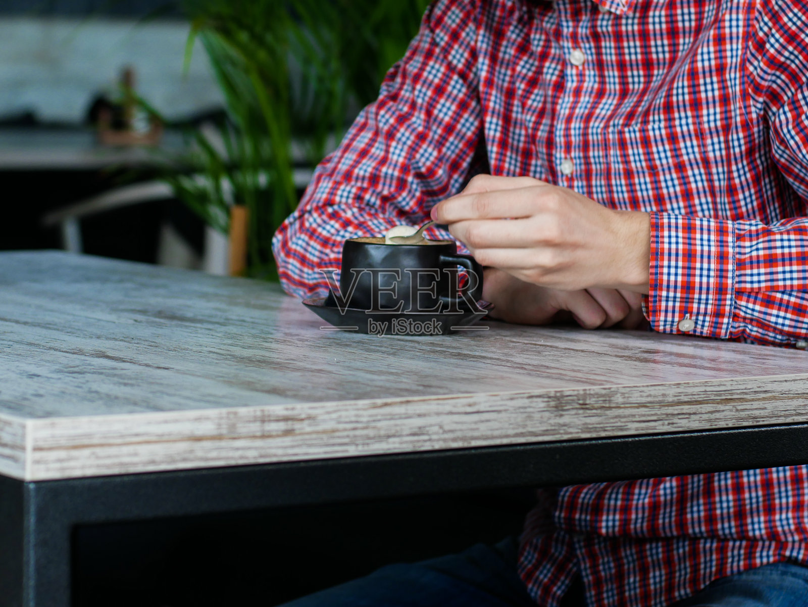 男子的手往卡布奇诺杯里倒糖照片摄影图片