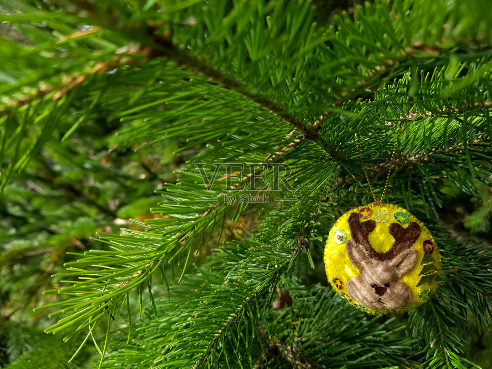 手工制作的驯鹿小雕像。云杉树枝上的圣诞节毛毡装饰。假日背景与副本空间。照片摄影图片
