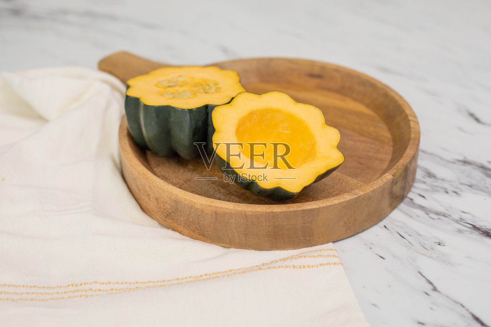 橡子南瓜在木托盘上切开;一半的种子挖出来了照片摄影图片