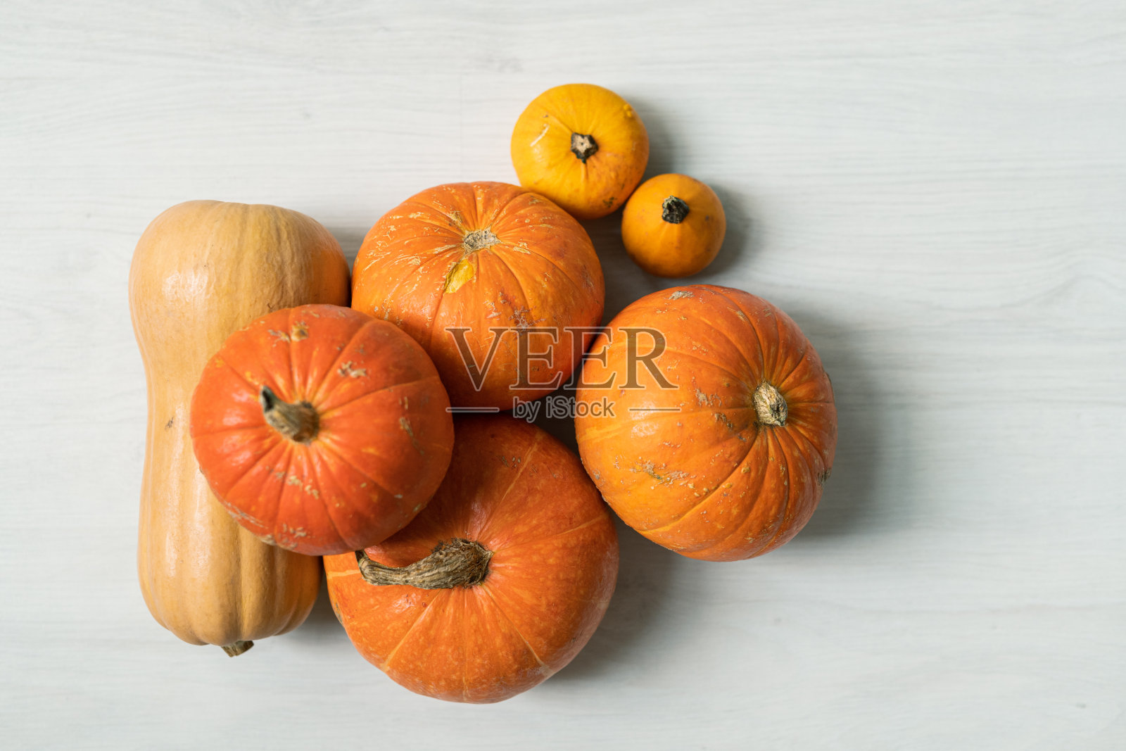 把橙色的大南瓜和两个黄色的小南瓜堆在白色的背景上照片摄影图片