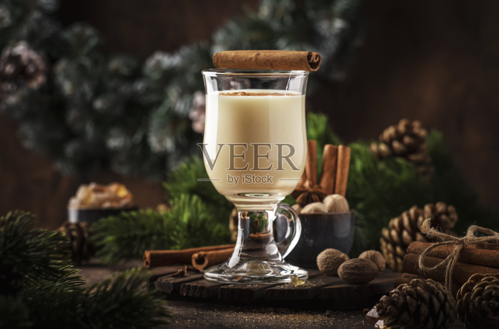 新年或圣诞节蛋酒鸡尾酒-冬天或秋天的热饮料牛奶，鸡蛋和黑朗姆酒，洒肉桂和肉豆蔻在一个玻璃杯的木制背景，节日装饰照片摄影图片