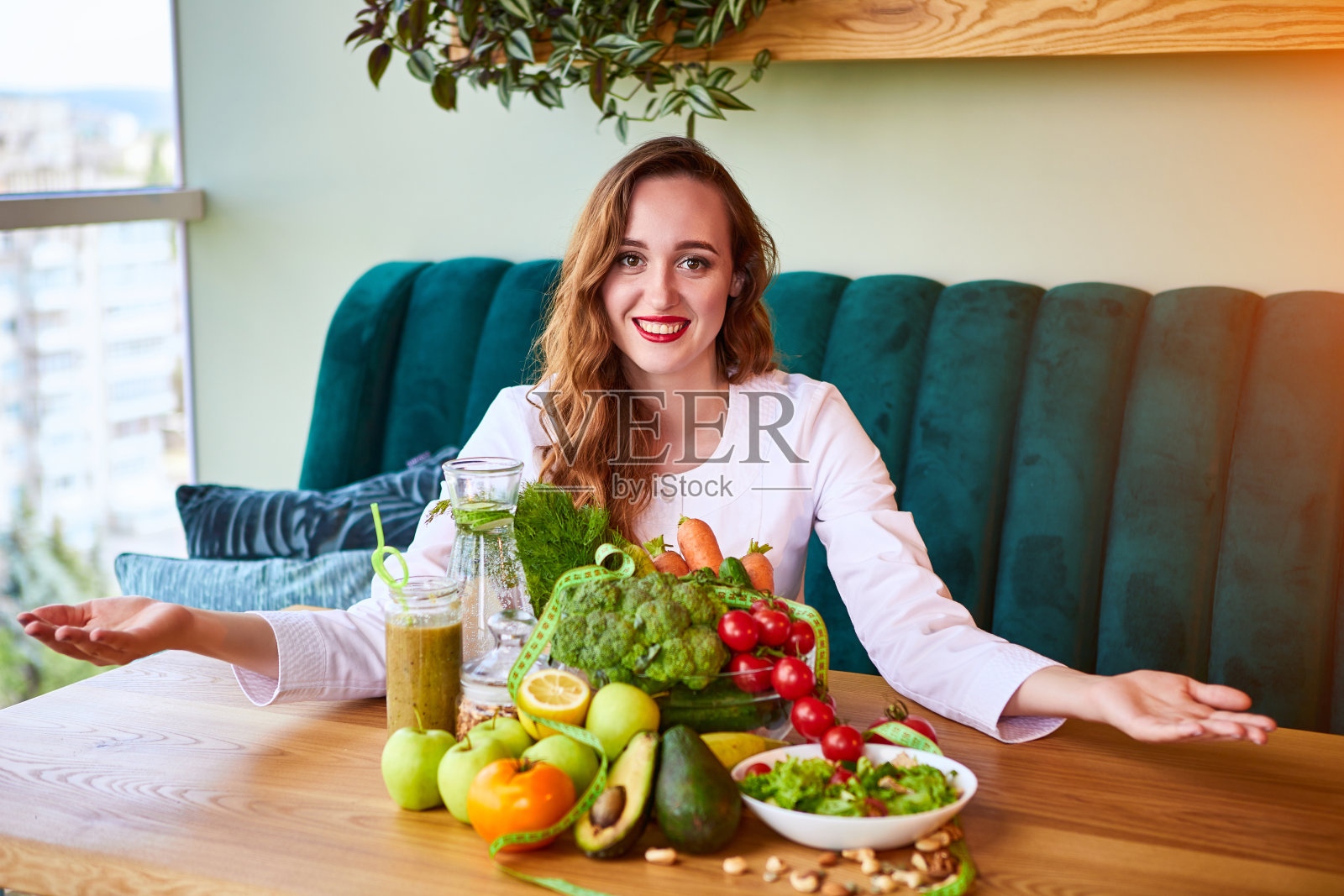 穿着医疗制服，带着卷尺制定饮食计划的女性营养师坐在绿色办公室里，背景是不同的健康食品成分。减肥和正确的营养观念照片摄影图片