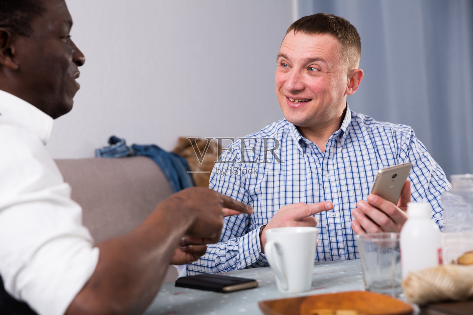 微笑的人与电话讨论与非洲朋友在家里照片摄影图片