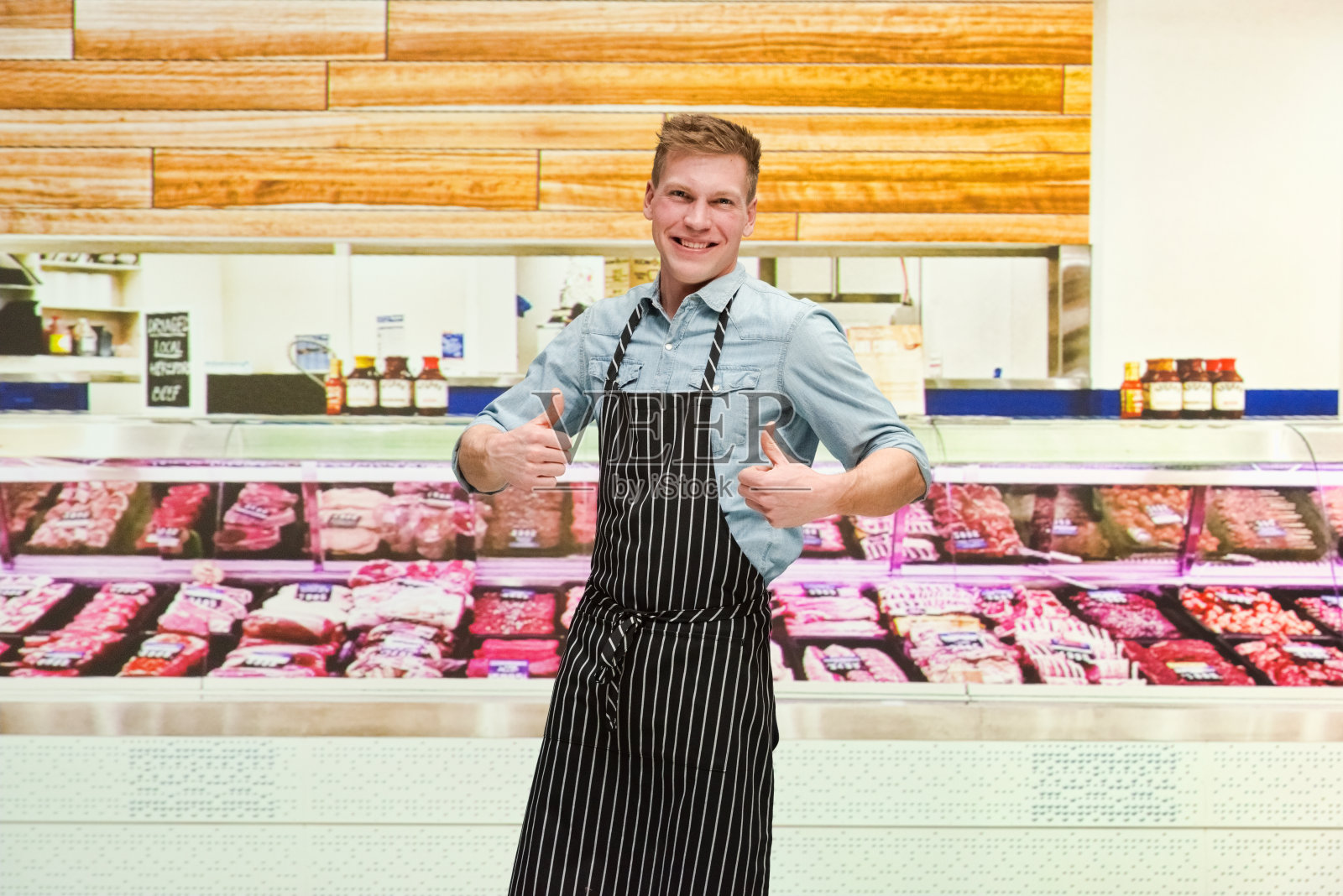 腰部以上/一人仅/一人20-29岁英俊的人白人男性/年轻男性屠夫/肉店老板/熟食店/市场-零售空间/冷藏区/超市中的商店/零售/食品照片摄影图片