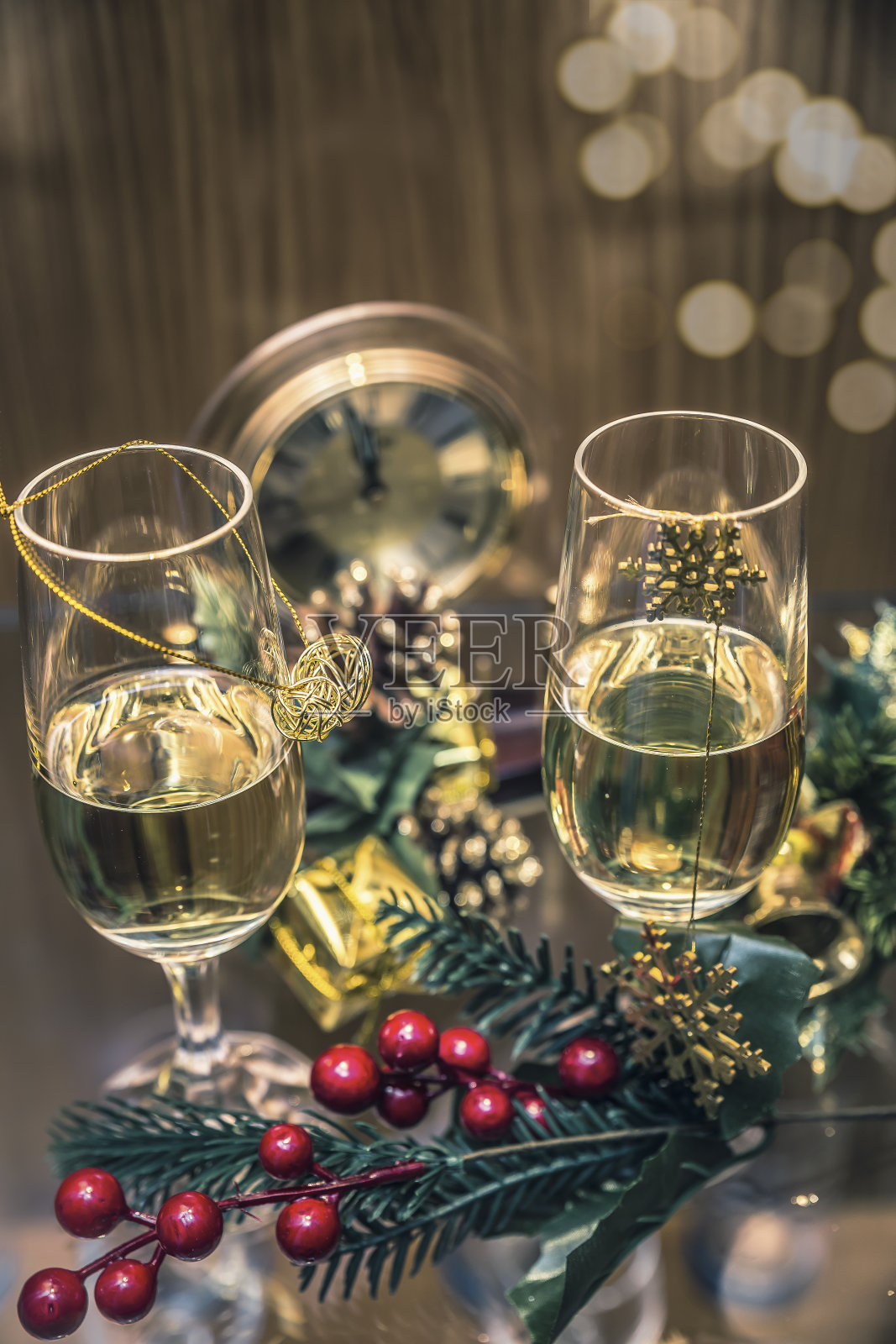 两杯香槟和冬青树在午夜时分的钟旁庆祝新年照片摄影图片