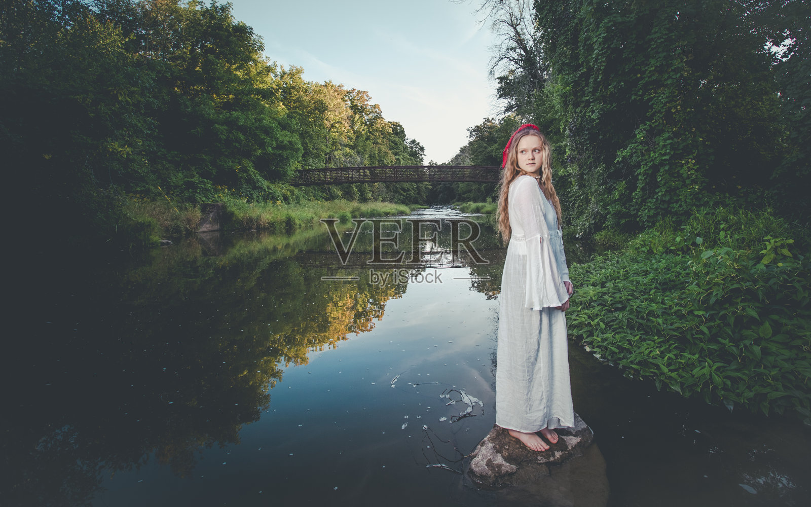 一个金发女人站在一条平静的河边照片摄影图片