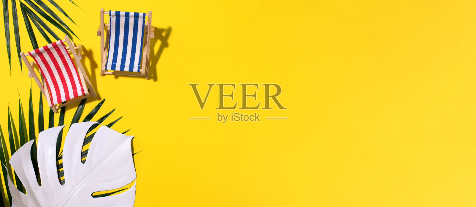 甲板上的椅子有坚硬的阴影，在黄色的纸背景上有怪物和棕榈叶。平铺和复制空间。夏季旅游度假概念。最小的组成照片摄影图片