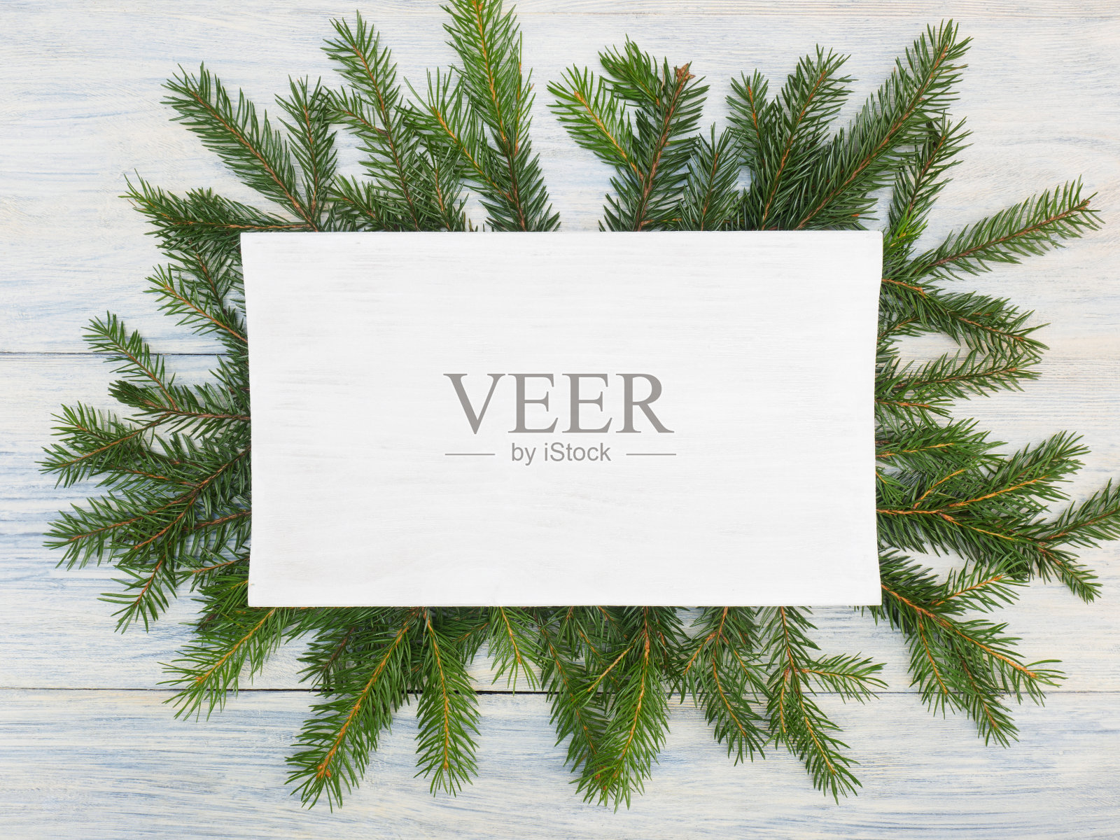 白木背景上印有铭牌的冷杉树枝。寒假的概念照片摄影图片