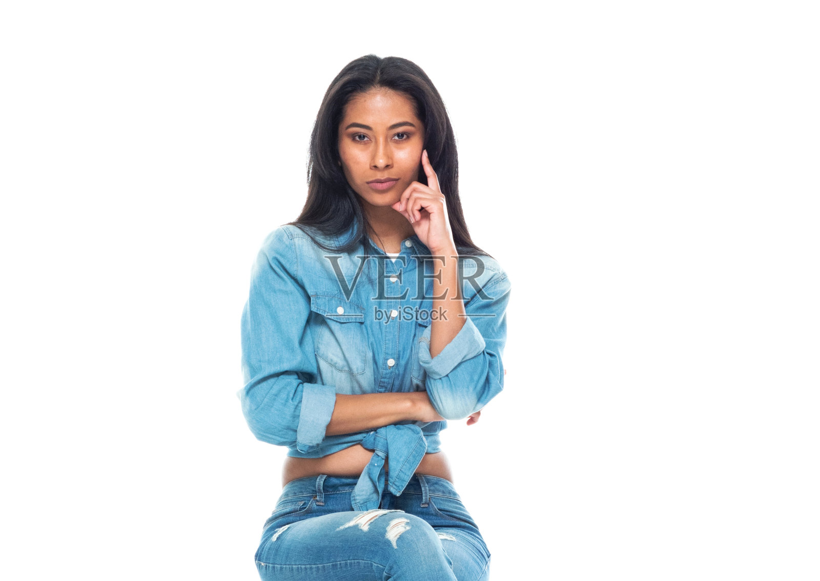 腰部以上的20-29岁美丽的拉丁美洲和西班牙裔的年轻女性/女性休息在白色的背景，穿着双牛仔布和高跟鞋，正在思考/凉爽的态度/坐在凳子上照片摄影图片