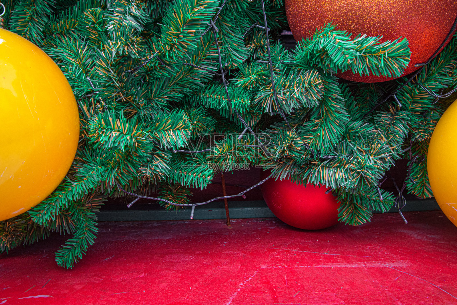 圣诞树的装饰地板上挂着黄色和红色的球。照片摄影图片