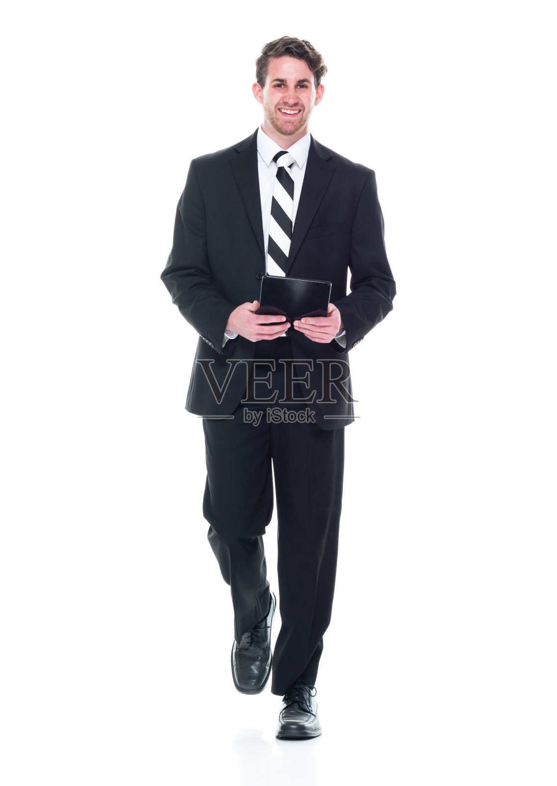 正面视图/看相机/全长/一个20-29岁的成年人英俊的人白种年轻男子/男性经理/商人/商人走在白色背景穿着西装和使用数字平板电脑照片摄影图片