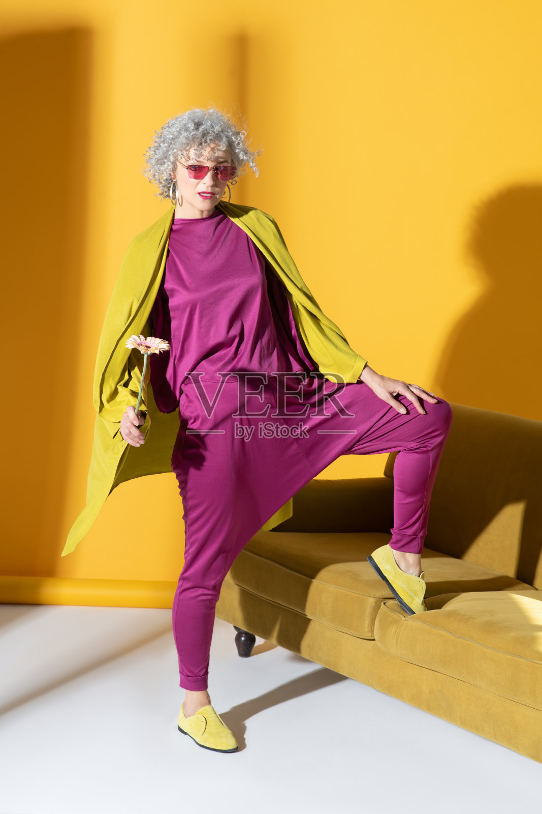 穿着粉红色衣服的时髦女人站在沙发旁边照片摄影图片