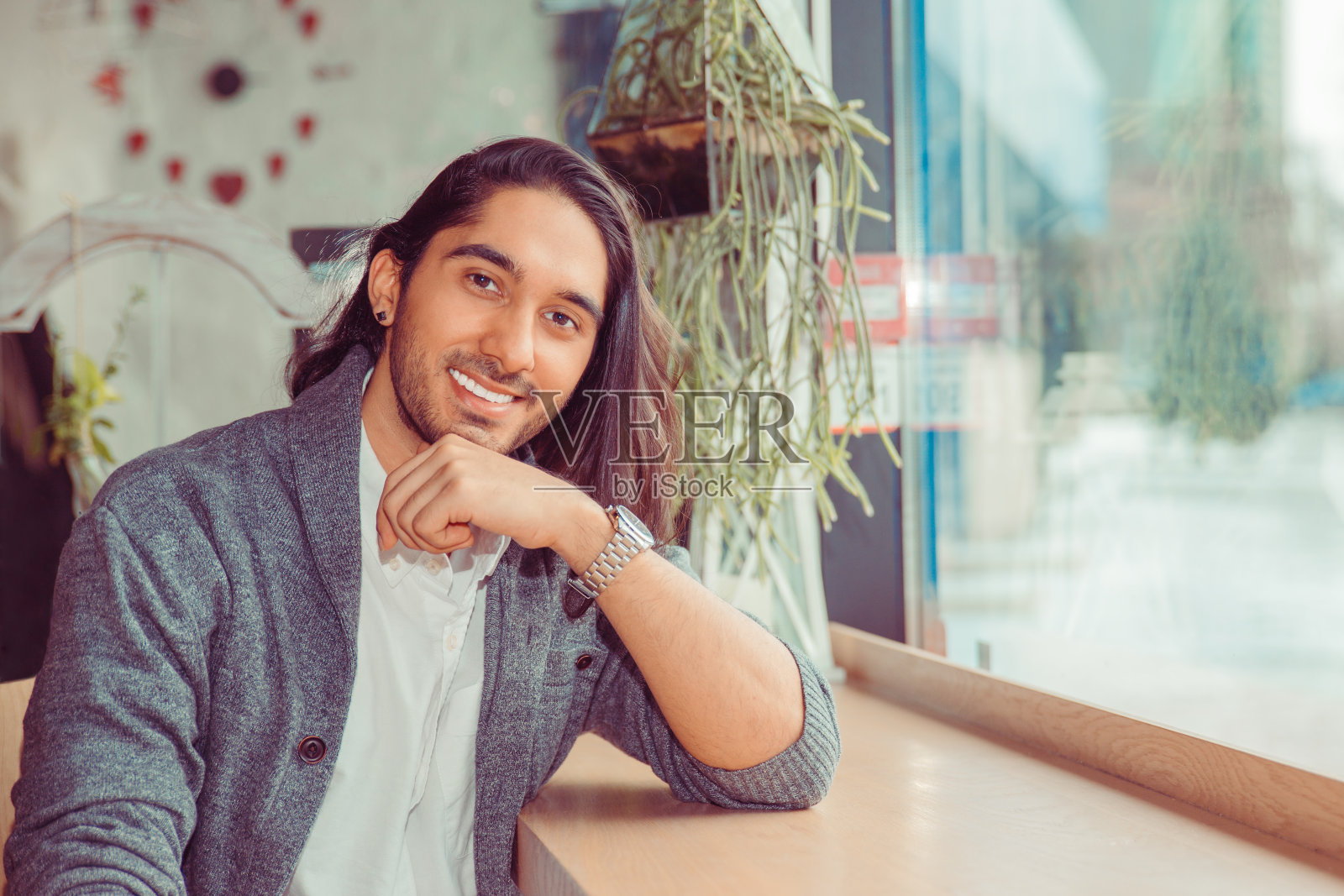 30岁的男人坐在咖啡店或客厅靠窗的桌子上，微笑地看着你的相机，照片摄影图片