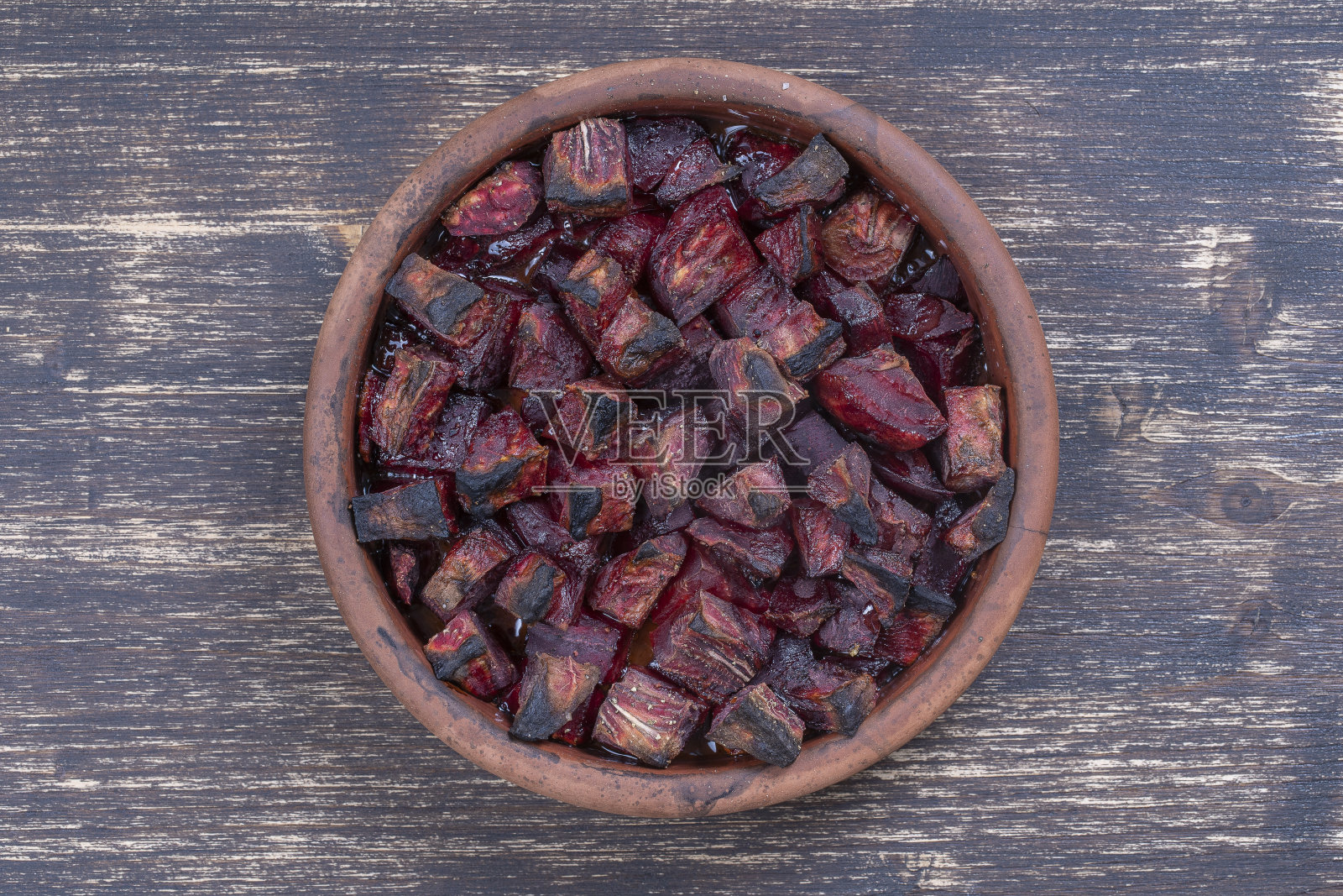 烤红甜菜根和蜂蜜放在木桌上，特写。陶瓷碗与紫色甜菜片背景，俯视图照片摄影图片