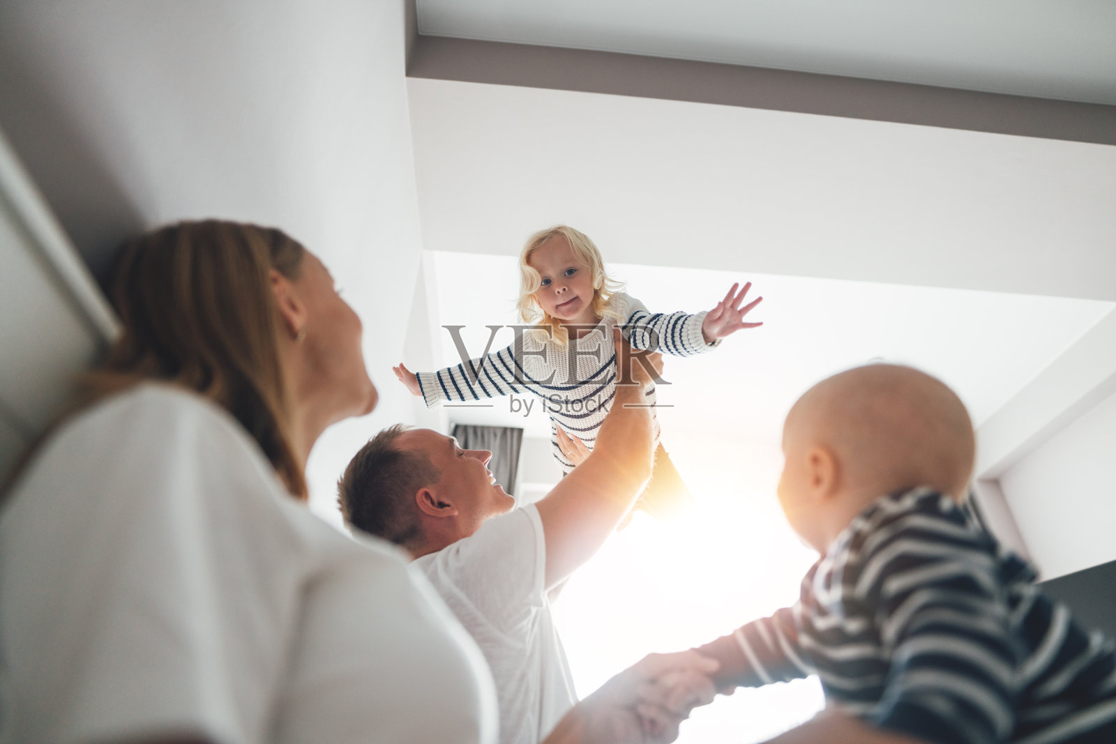 幸福的家庭和孩子一起在家里玩的时间。年轻的爸爸和女儿一起玩，把她抱在手里照片摄影图片