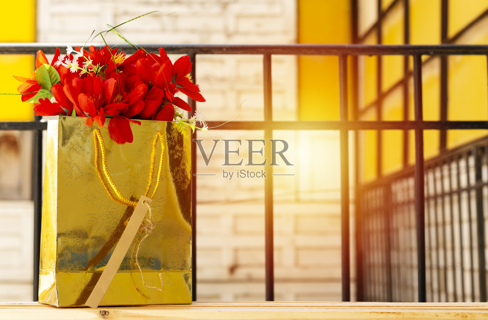 木桌上放着一个金色的礼品袋，上面挂着空的标签照片摄影图片