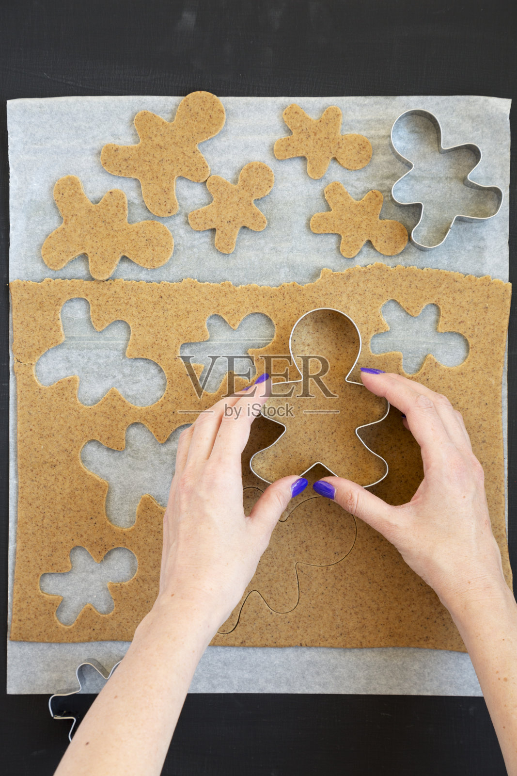 女人在一个黑色的表面上做圣诞饼干，俯视图。从上面的开销。照片摄影图片