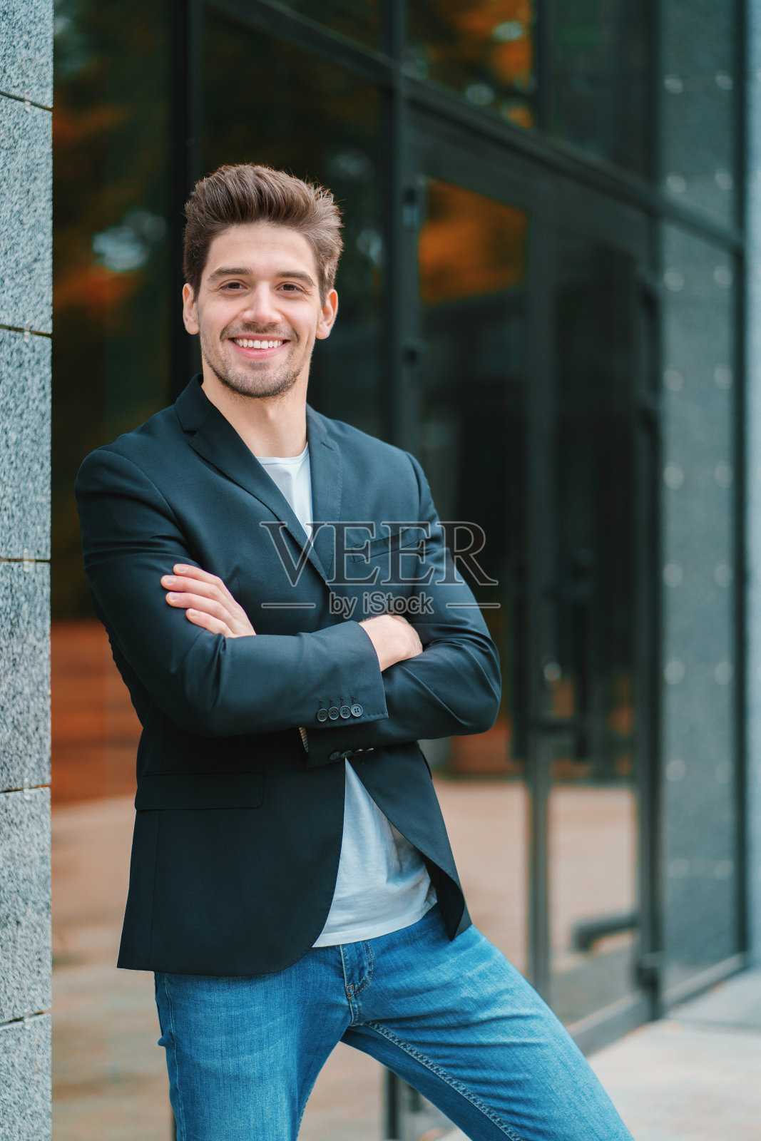 一个年轻的成功商人在城市沉思的肖像。在办公楼背景上穿着商务夹克的男人。英俊的人考虑工作照片摄影图片