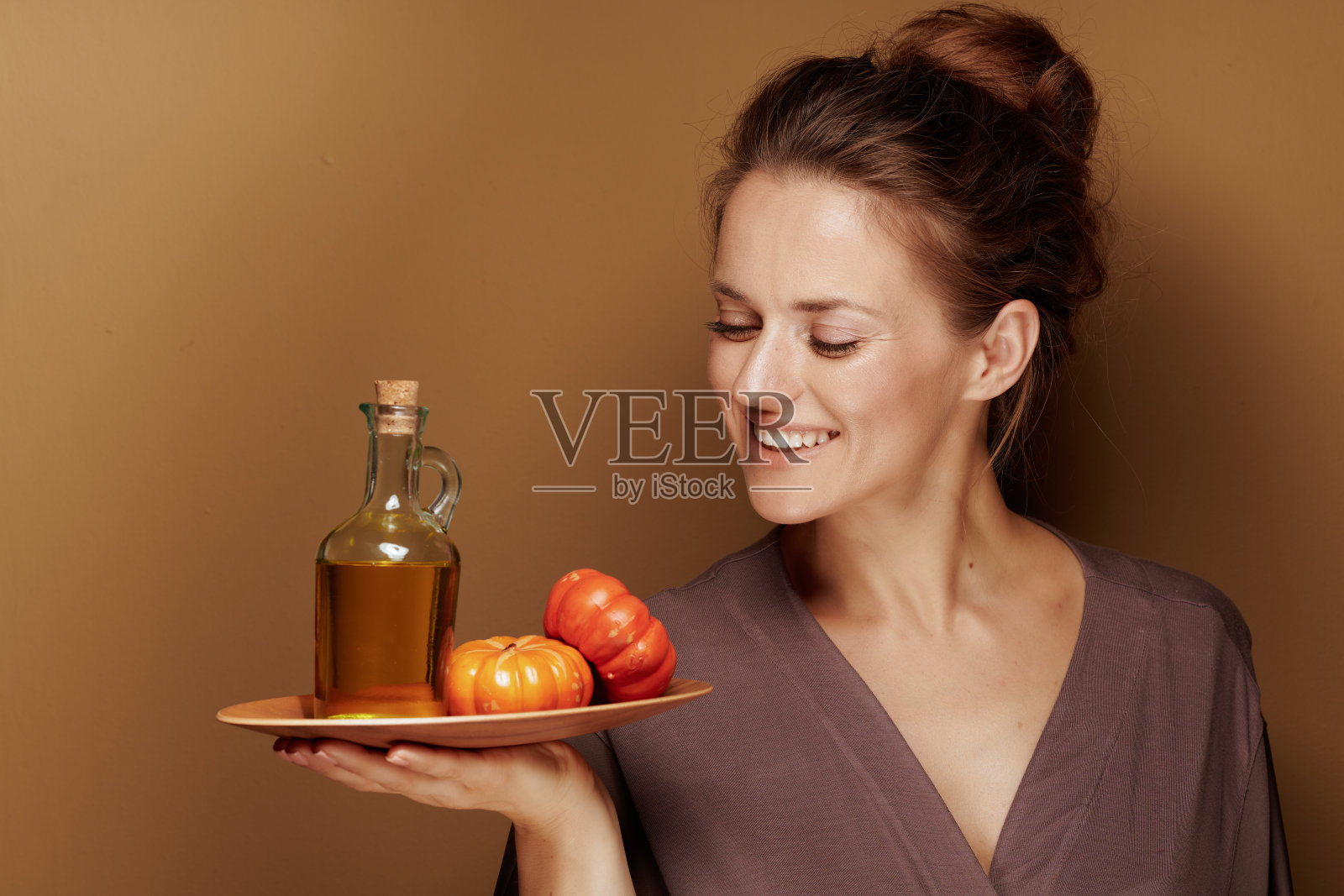 一位中年妇女在棕色背景下看着南瓜油照片摄影图片