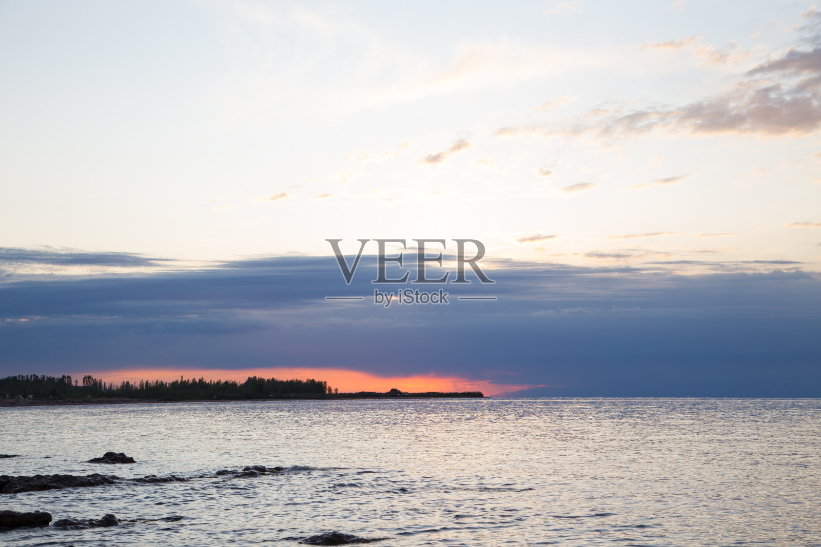 山上湖上美丽的日落。吉尔吉斯斯坦、吉湖。明亮的天空，暖色的背景。照片摄影图片